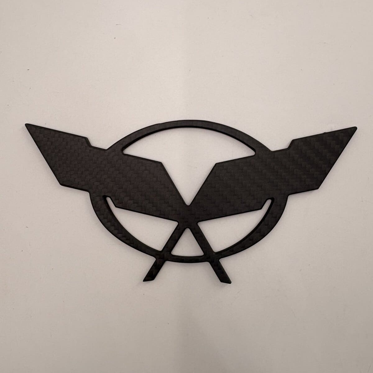 CNC machined matte carbon fiber car emblem with internal cutouts.jpg
